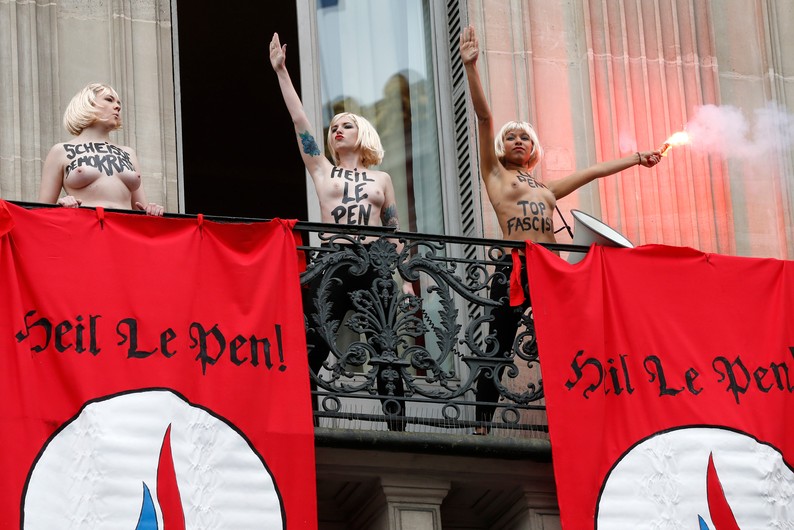1er mai. Y avait du monde au balcon pour le discours de Marine Le Pen à Paris ! Les militantes Femen seront évacuées avec force par le service d'ordre du Front national. (Photo AFP/Thomas Samson)