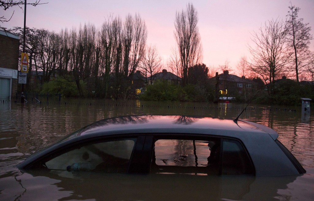 A submerged car is pictured on a residential road next to the River Foss after it burst it's banks in York, northern England, on December 28, 2015. British Prime Minister David Cameron visited the flood-hit historic city of York on Monday as cities, towns and villages across northern England battled to get back on their feet following devastating storms. Around 500 properties were flooded in York, one of Britain's top tourist attractions, on Sunday as two rivers burst their banks. Some residential streets became so inundated that cars were covered up to their roofs. AFP PHOTO / JUSTIN TALLIS