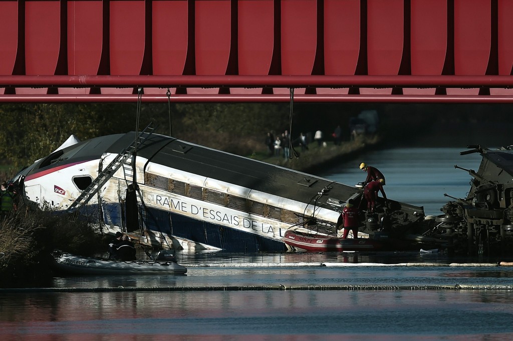 (FILES) This file photo taken on November 15, 2015 shows emergency personnel working at an accident scene on November 15, 2015 where a high-speed TGV train coach and engine carriage lie, in a canal in Eckwersheim near Strasbourg, northeastern France, after derailing on November 14, causing the death of ten people during a test conducted by technicians and, French railway operator SNCF said.  The tests on the high-speed line (LGV) east-European connecting Paris to Strasbourg, which had caused a fatal accident on 14 November, resumed on February 29, 2016, with an expected commissioning in July, said on March 1, 2016 a SNCF network spokesman to AFP. / AFP / FREDERICK FLORIN