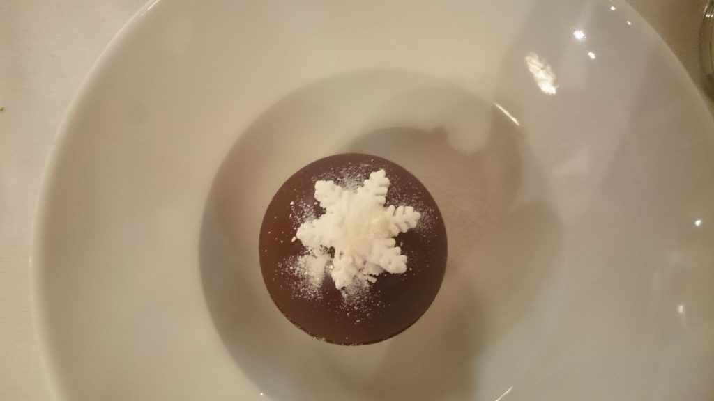 La coque au chocolat, remplie de glace cassis et de meringue, prête à fondre sous un coulis de marron chaud.