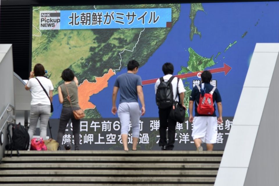 Des passants regardent le 29 août 2017 à Tokyo un écran montrant la carte du Japon et de la péninsule coréenne, d'où est parti le missile qui a survolé l'archipel. (Photo : AFP)