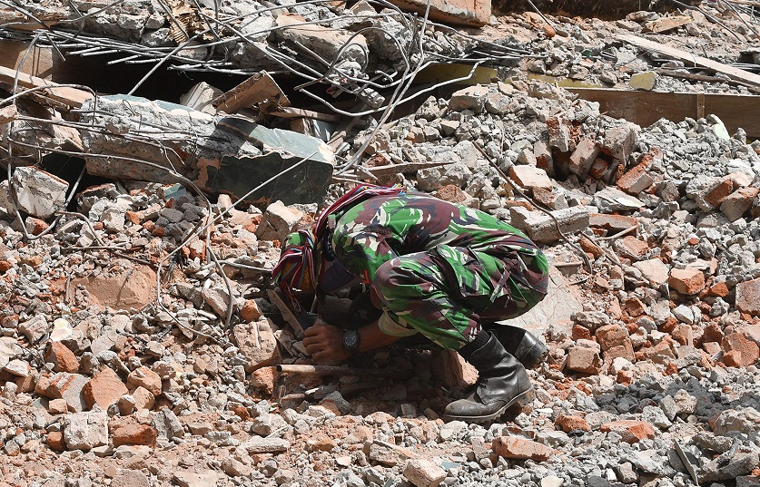 Un soldat indonésien participant à des opérations de recherche et de sauvetage recherche des victimes du tremblement de terre dans les décombres de Tanjung, sur l'île de Lombok, le 9 août 2018. (Photo : AFP)