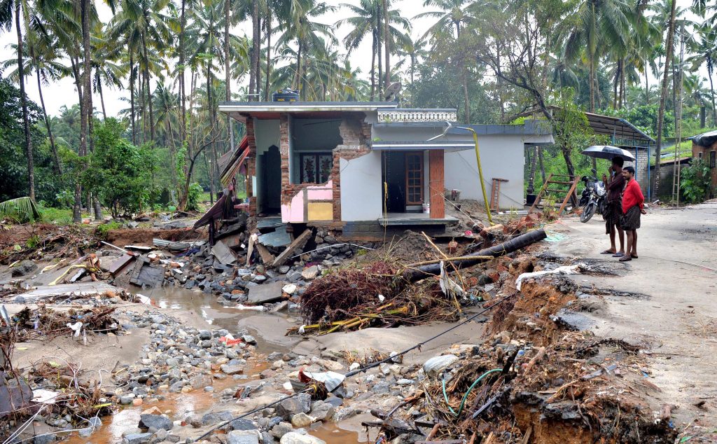 Des Indiens regardent une habitation détruite par un glissement de terrain dans le village de Kannapanakundu, dans l'Etat du Kerala (sud), le 18 août 2018.
